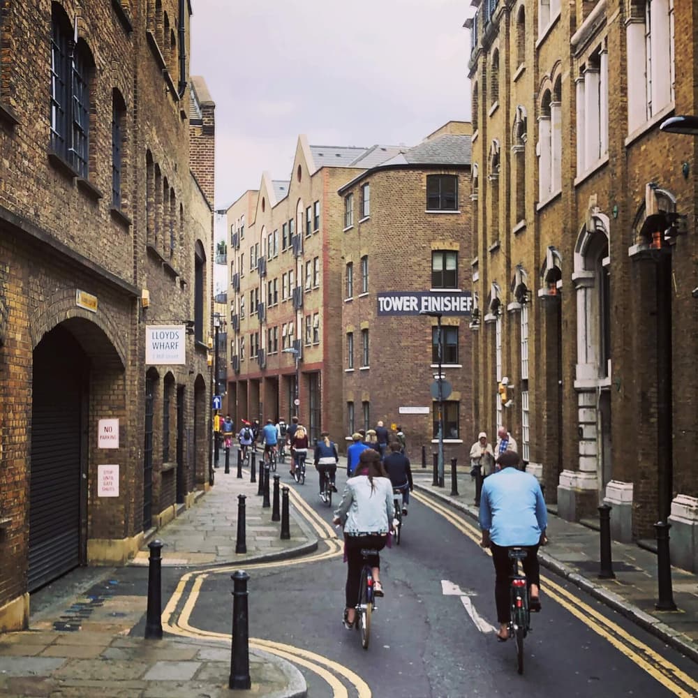 people riding vintage bikes down a london street on a river thames bike tour