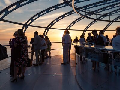 people enjoying the views out of the pod on the i360 in brighton as the sun is setting