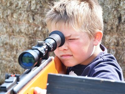 young boy aiming an air rifle on a spy camp experience day for kids