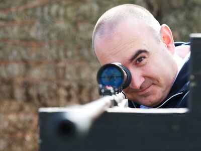 man aiming an air rifle while on a spy camp experience day for adults