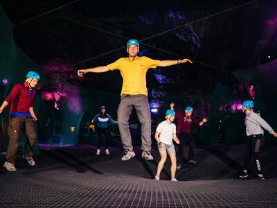 people bouncing on a trampoline inside a cave on a bounce below experience day