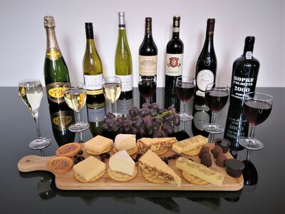 bottles of red wine and port lined up with a platter of cheese and crackers on a wine tasting experience with wine cottage