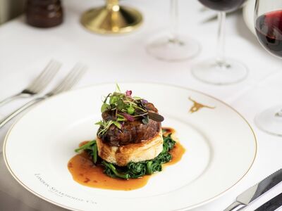 a meal of steak on top of mashed potato and greens at marco pierre white's london steakhouse company