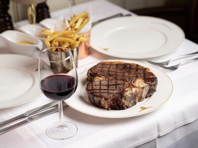 a steak meal with fries on the side and a glass of wine at marco pierre white's london steakhouse company