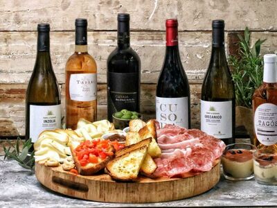 a selection of wine bottles with a sharing board of meats, bread and cheese for a trip to sicily wine and nibbles gift experience