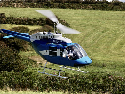 a blue and white helicopter flying over fields as part of a chopper experience