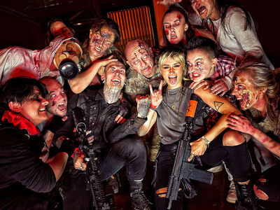 visitors posing for photo with zombies covered in blood as part of a zombie survival experience