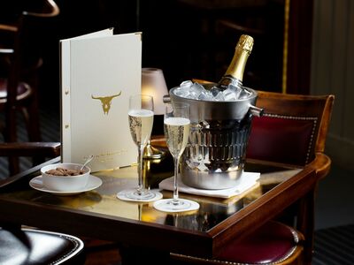 a champagne bucket with two glasses of champagne on a table with a menu