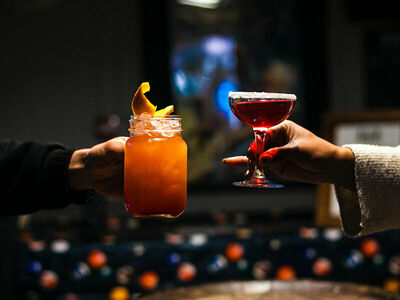 a shot of two arms each holding a different cocktail