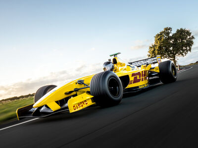 a yellow jordan f1 race car on a race track against a clear sky background