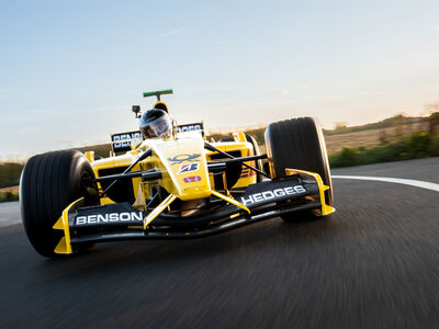 a front view of a yellow and black formula one race car on a race track as part of a driving experience