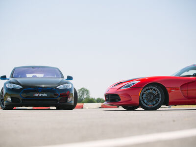 two supercars, a tesla and a viper, side by side on a race track.