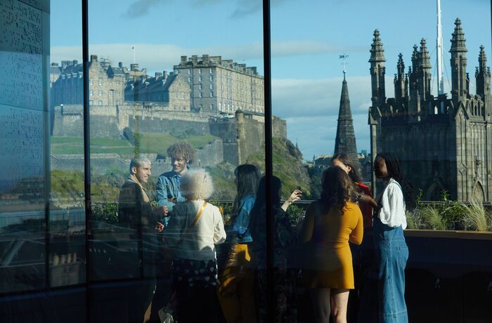 group of people enjoying a drink on the balcony overlooking edinburgh castle