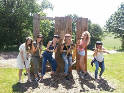 group of women posing in front of wooden boards holding axes as part of an axe throwing experience