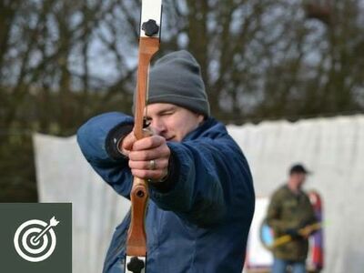 man holding a bow and arrow aiming towards the camera as part of an archery experience