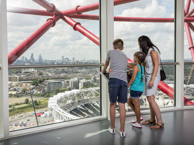 a woman and two children looking out over london at the top of the arcelormittal orbit