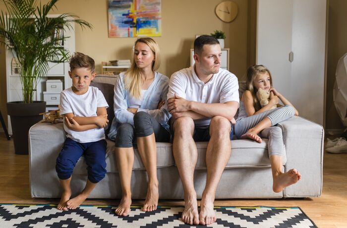 family looking bored sitting on sofa at home