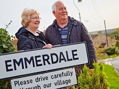 couple posing next to emmerdale sign on the emmerdale village tour