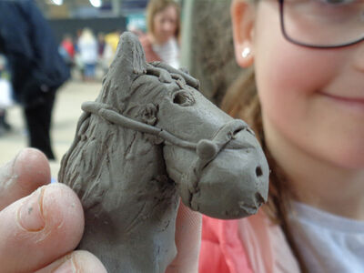 a young girl showing off the horses head she has made on a clay modelling experience day